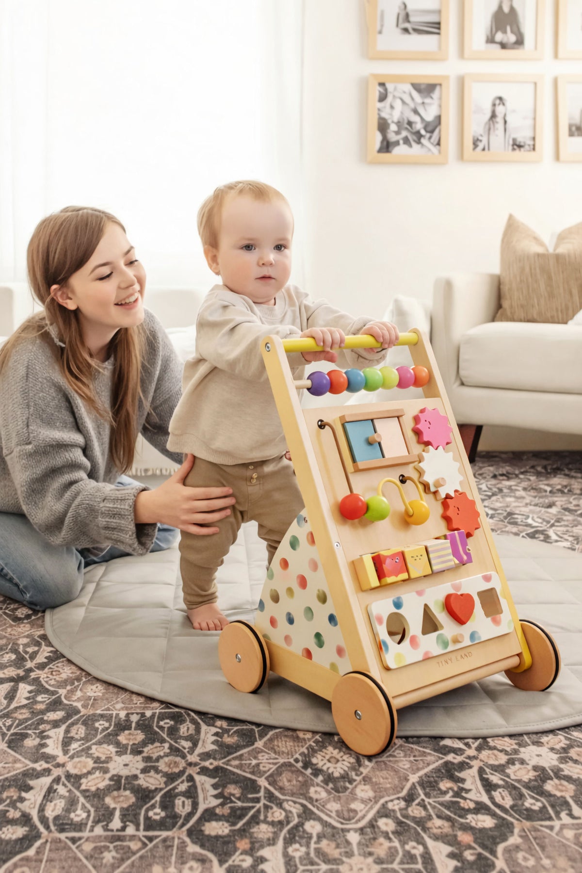 A toddler uses a colorful wooden baby walker with activity features, while a caregiver supports them in a cozy indoor.