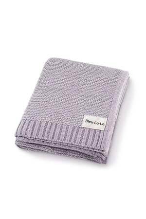 Light purple knit baby blanket with ribbed edges, folded neatly, featuring a Bleu La La label.