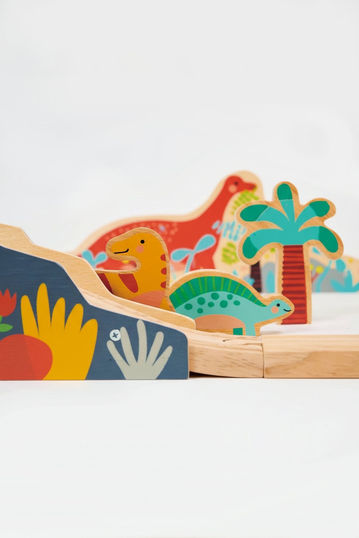 Colorful wooden dinosaurs and trees on a wooden railway track, featuring playful designs and vibrant colors.