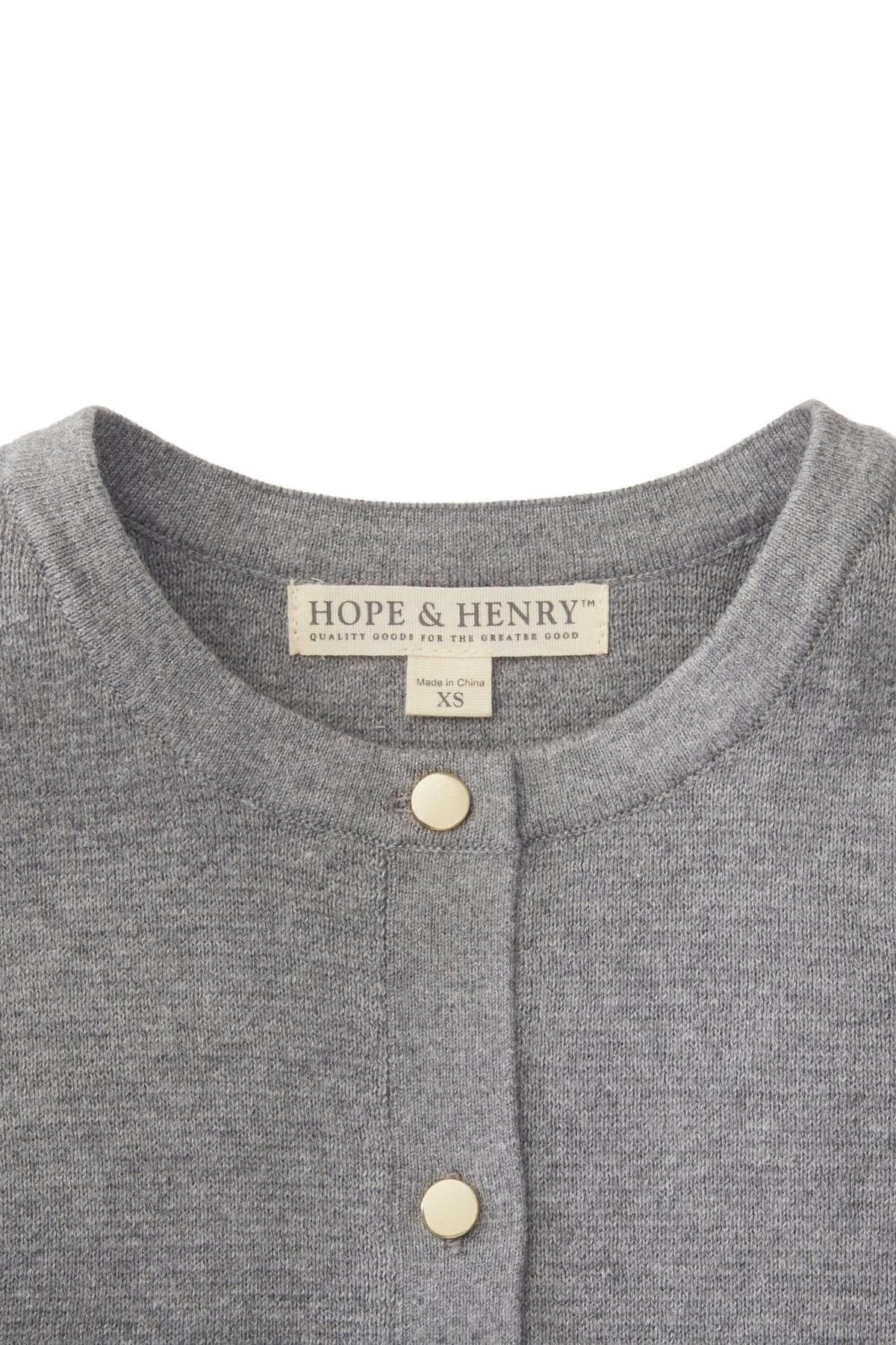 A close-up of a gray cardigan by Hope & Henry, featuring a fine gauge organic cotton fabric. The neckline includes two elegant gold buttons and a label indicating size XS.