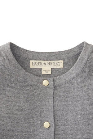 A close-up of a gray cardigan by Hope & Henry, featuring a fine gauge organic cotton fabric. The neckline includes two elegant gold buttons and a label indicating size XS.