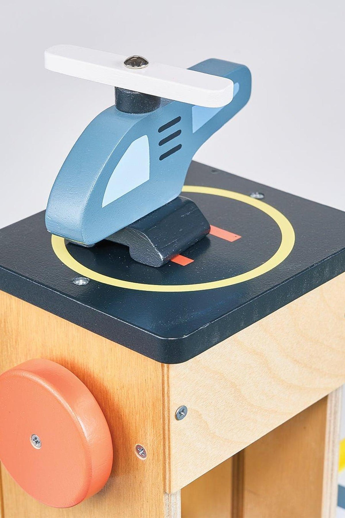 Wooden toy helicopter on a black helipad with a yellow circle, attached to a wooden structure.