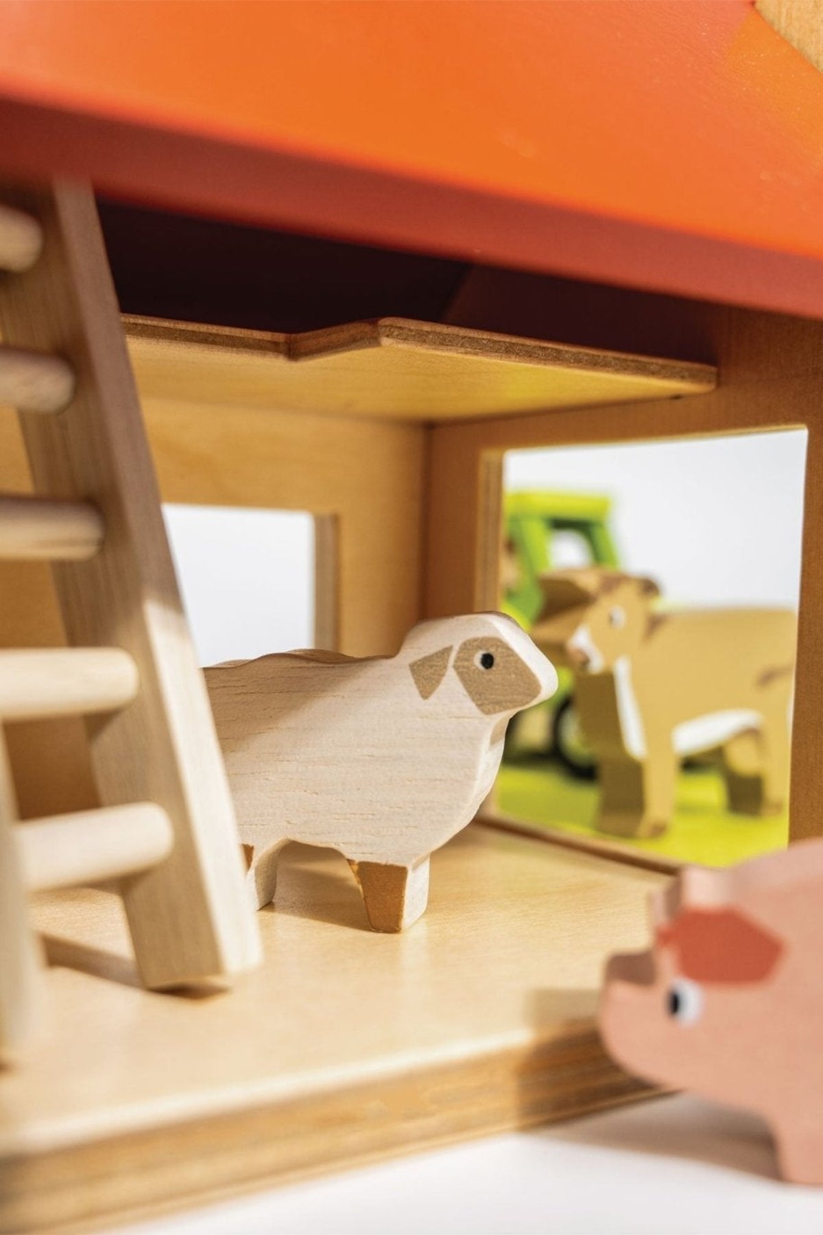 Wooden toy barn with a sheep and a pig on a blurred background