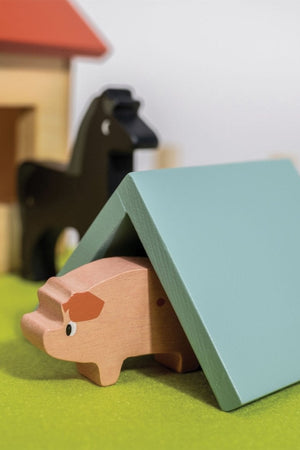 Wooden toy barn with a red roof, horse, and pig on a green surface.