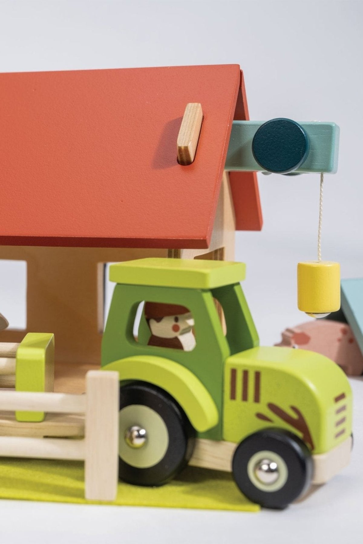 A colorful wooden toy farm set features a red-roofed barn and a green tractor with black wheels. The set encourages imaginative play for young children with its safe, eco-friendly materials.