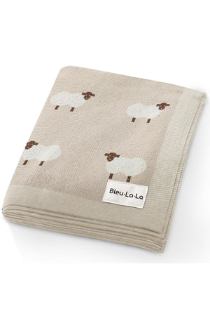 Beige knit blanket with sheep pattern, featuring a Bleu La La label on the corner.