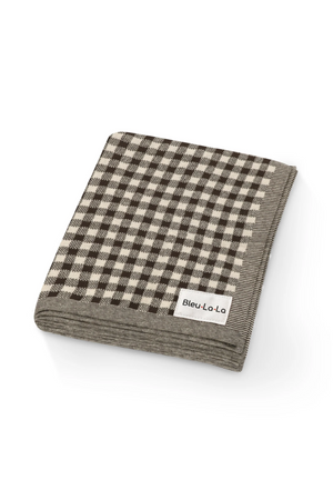 Folded checkered knit blanket with a black and cream pattern, featuring a Bleu La La label on the corner.