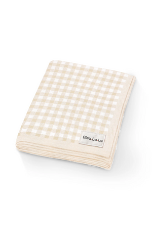 Folded beige and white checkered knit blanket with a Bleu-Lo-La label, made from soft cotton fabric.
