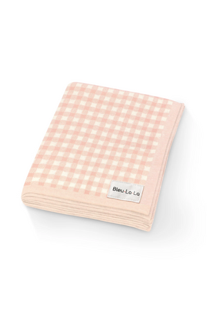 Pink and white checkered knit blanket folded neatly, featuring the brand tag Bleu Lo Lo on the corner.