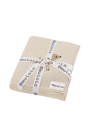 A beige knit blanket with a small deer design, tied with a branded ribbon featuring Bleu-La-La.