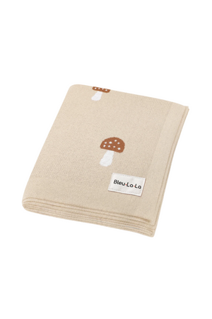Beige knit blanket with brown mushroom patterns and a Bleu La-La label, folded neatly.