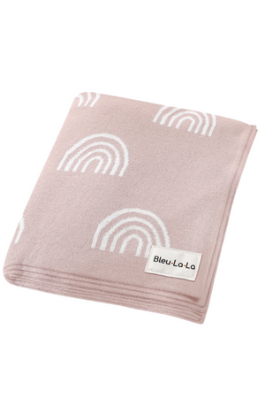Light pink swaddle blanket with white rainbow pattern, featuring a Bleu La La label, made from soft fabric.