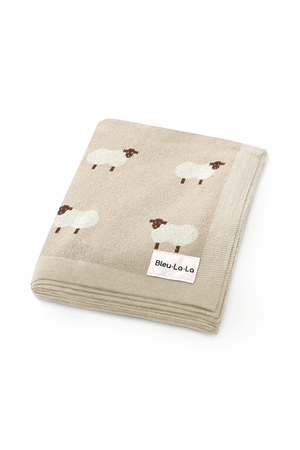 Beige knit blanket with sheep patterns, labeled Bleu-La-La, made from soft, breathable cotton fabric.