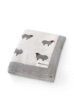 Folded grey blanket with sheep pattern and Bleu-La-La label, featuring a striped border. Made from soft fabric.
