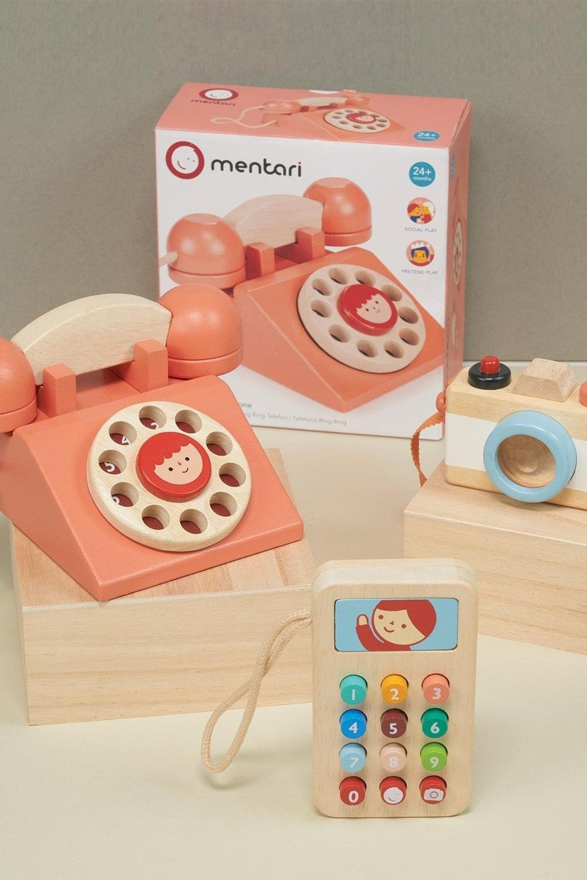 Wooden toy set with a retro telephone, colorful mobile phone, and camera, displayed in a playful setting.