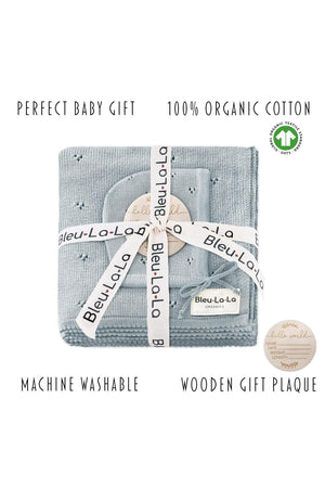 A neatly folded blue pointelle blanket and hat set, wrapped with branded ribbon, includes a wooden gift plaque.