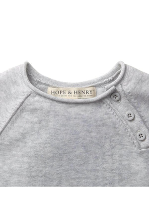 Close-up of a light heather grey organic cotton baby romper by Hope & Henry, featuring a soft neckline, rolled edges, and decorative buttons at the shoulder.