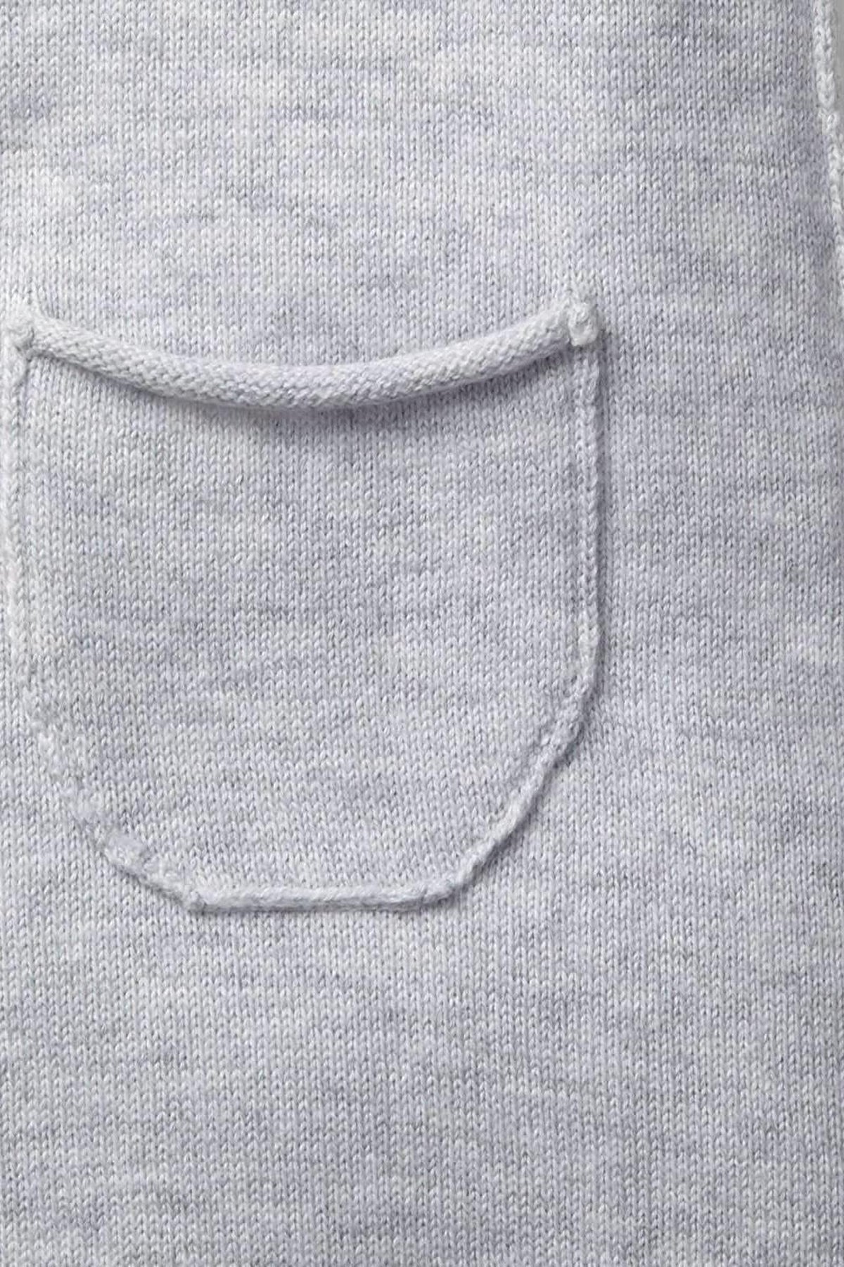 Close-up of a light heather grey organic cotton fabric showcasing a soft rolled edge and a tiny pocket. The material appears gentle and comfortable, suitable for babies.