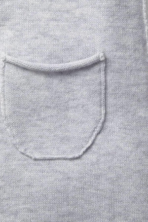 Close-up of a light heather grey organic cotton fabric showcasing a soft rolled edge and a tiny pocket. The material appears gentle and comfortable, suitable for babies.