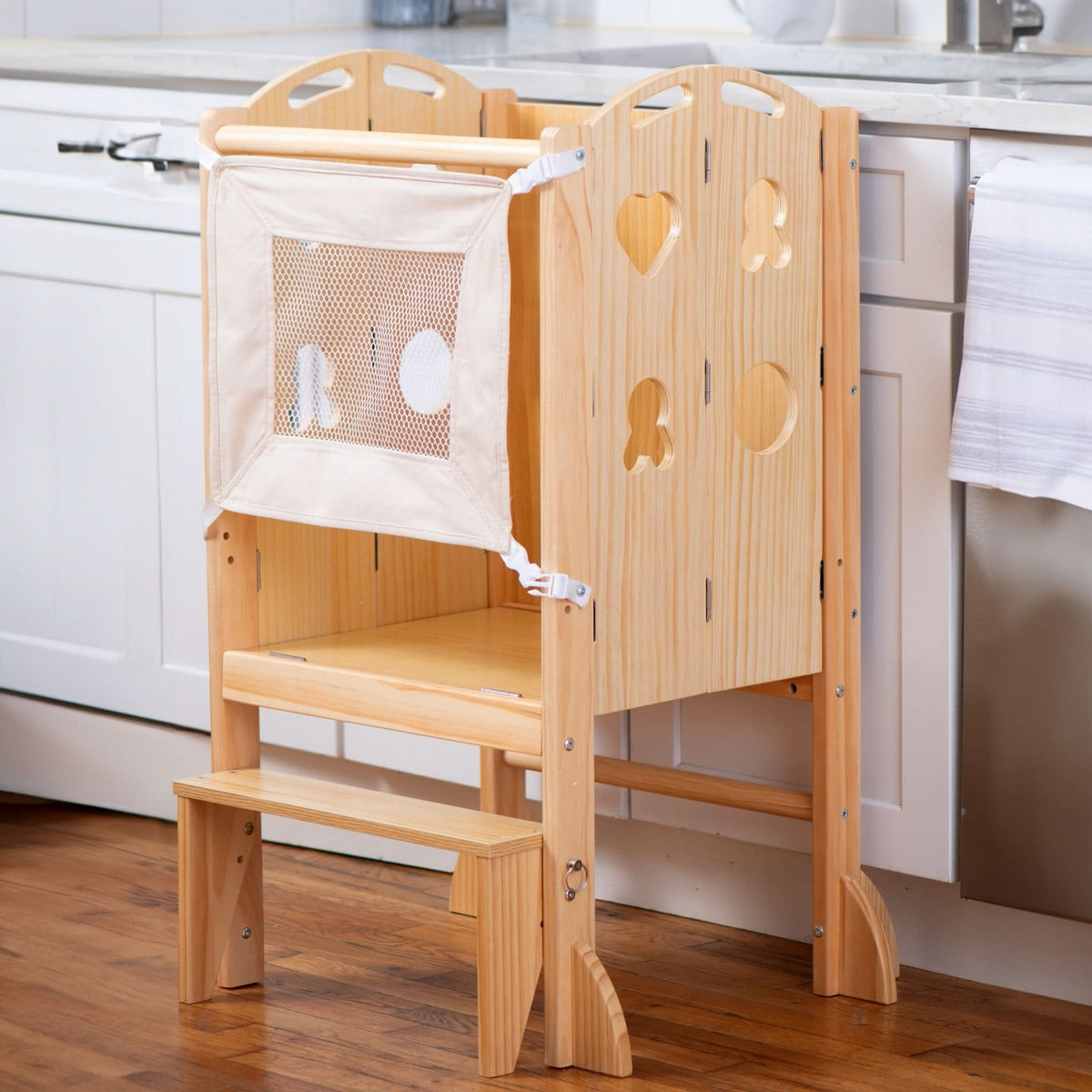 Laurel 4-in-1 Foldable Kitchen Tower in natural wood features a step stool, slide, and chalkboard. It includes a fabric safety mesh and is designed for toddlers to promote independence.