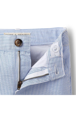 Close-up of the waistband and zipper of blue and white striped organic cotton seersucker shorts, featuring a faux horn button and clean stitching, ideal for comfortable, stylish wear.