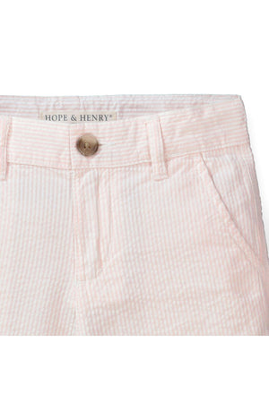 Close-up of light pink organic cotton seersucker shorts by Hope & Henry, featuring a faux horn button and subtle striped texture, designed for comfort and style in childrens casual wear.