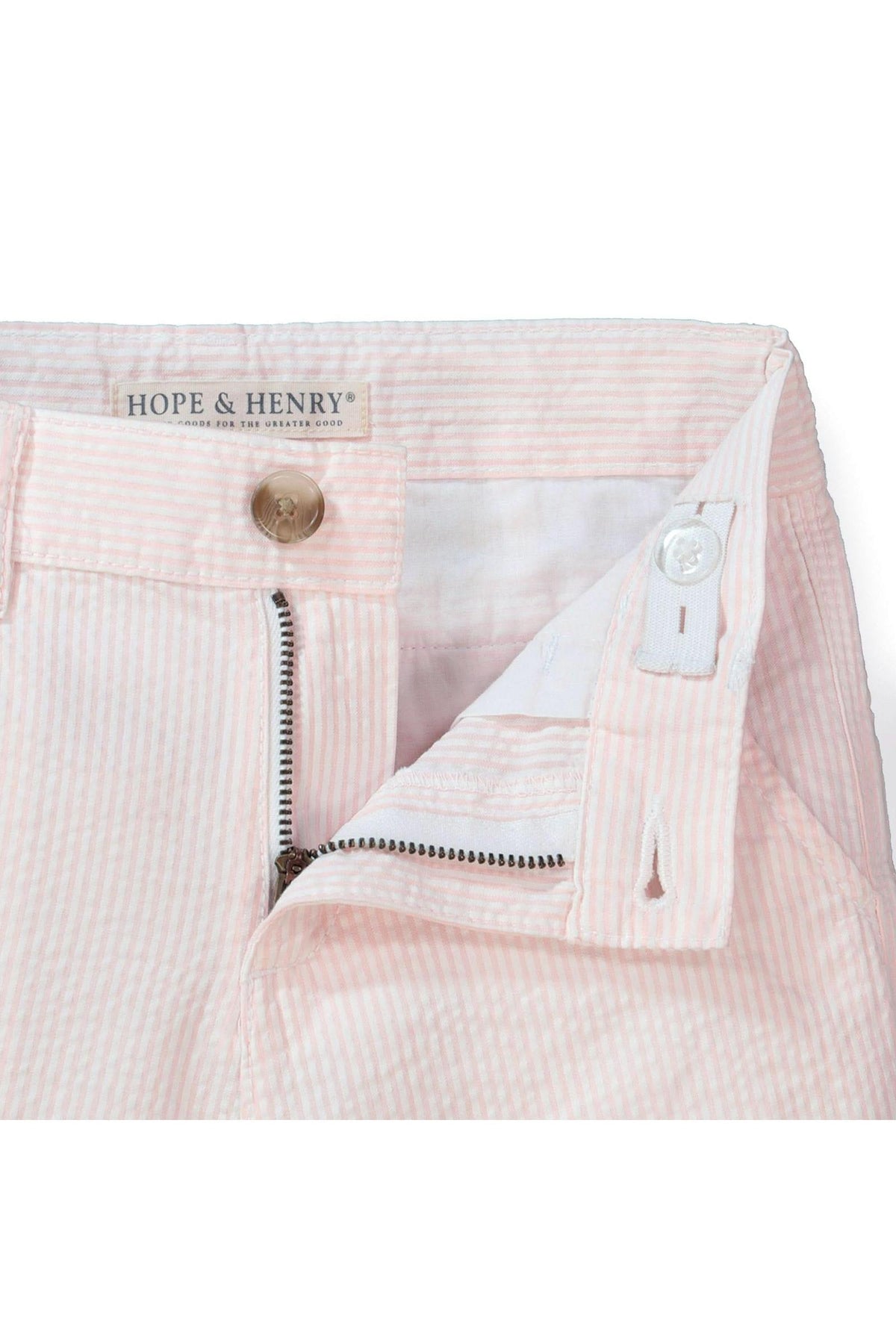 Close-up of light pink organic cotton seersucker shorts featuring a faux horn button and zipper detail, emphasizing the adjustable waistband designed for comfort and style. Ideal for everyday wear.