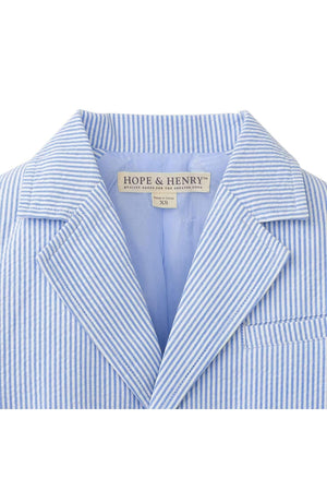 A close-up of a blue and white striped seersucker blazer, featuring a notch collar and a welt chest pocket.