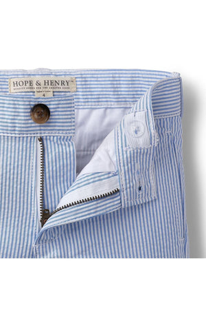 Close-up of blue and white striped seersucker fabric from Hope & Henry, showcasing the waistband, button, and zipper detail. Crafted from organic cotton, ideal for boys sizes 2T to 12.