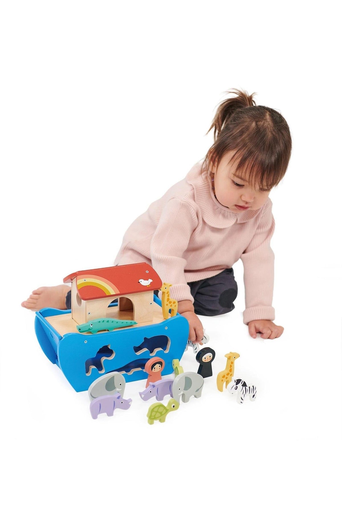 A child plays with a colorful wooden animal ark toy set, featuring various animal figures and a boat.