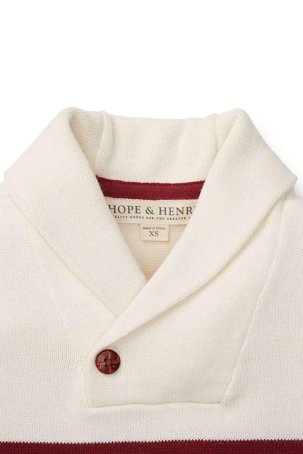 Close-up of a Hope & Henry ivory organic cotton shawl collar sweater featuring a brown button and a maroon stripe.