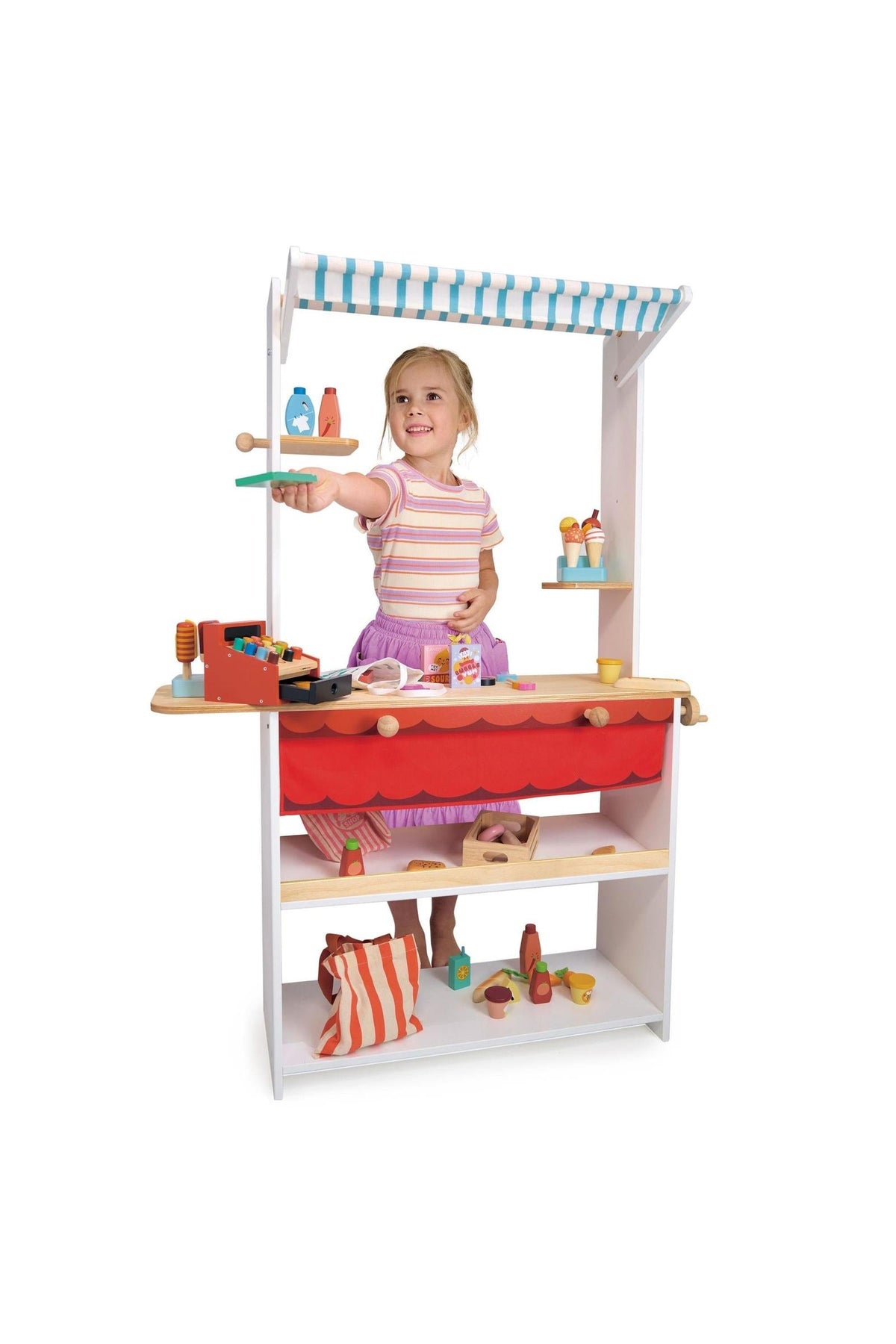 A child plays with a wooden shopkeeper stand, featuring colorful toy groceries and a striped canopy.
