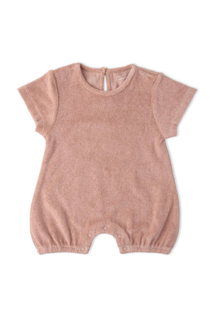 A soft clay-colored organic cotton short romper features short sleeves and a relaxed fit, ideal for warm weather and playful adventures. It includes snap closures for easy dressing.
