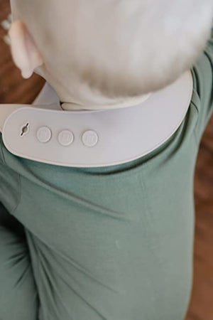 A baby wearing a gray adjustable silicone bib over a green outfit, viewed from above.