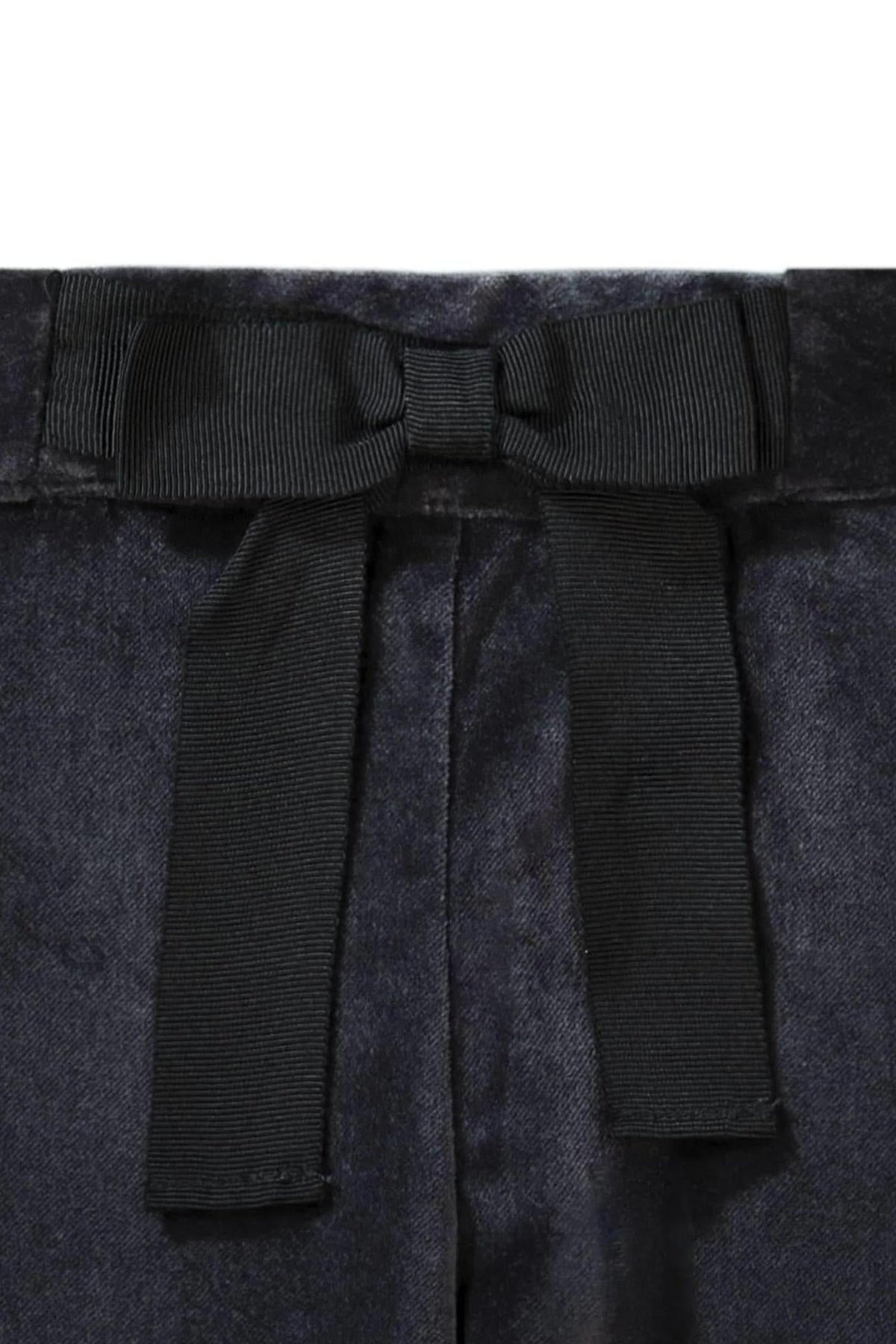 Close-up of black dressy pants featuring a decorative bow at the waist, showcasing a soft fabric texture.