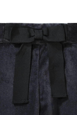 Close-up of black dressy pants featuring a decorative bow at the waist, showcasing a soft fabric texture.