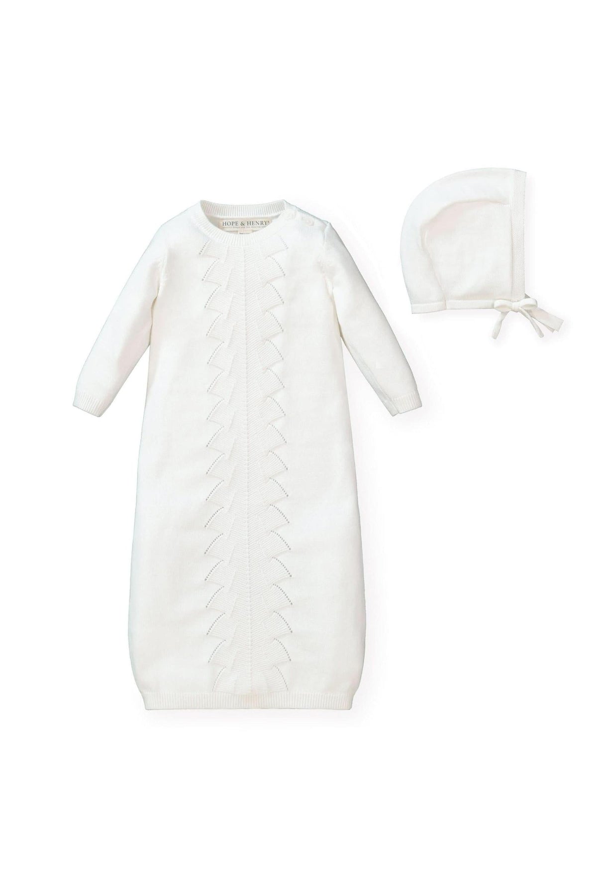 A soft white organic cotton sweater gown features delicate pointelle detailing and a coordinating bonnet with a pre-tied bow.