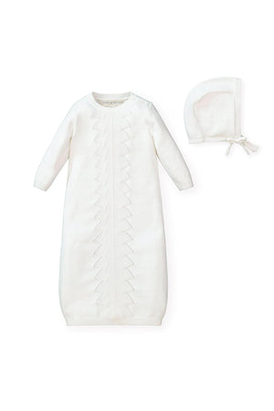 A soft white organic cotton sweater gown features delicate pointelle detailing and a coordinating bonnet with a pre-tied bow.