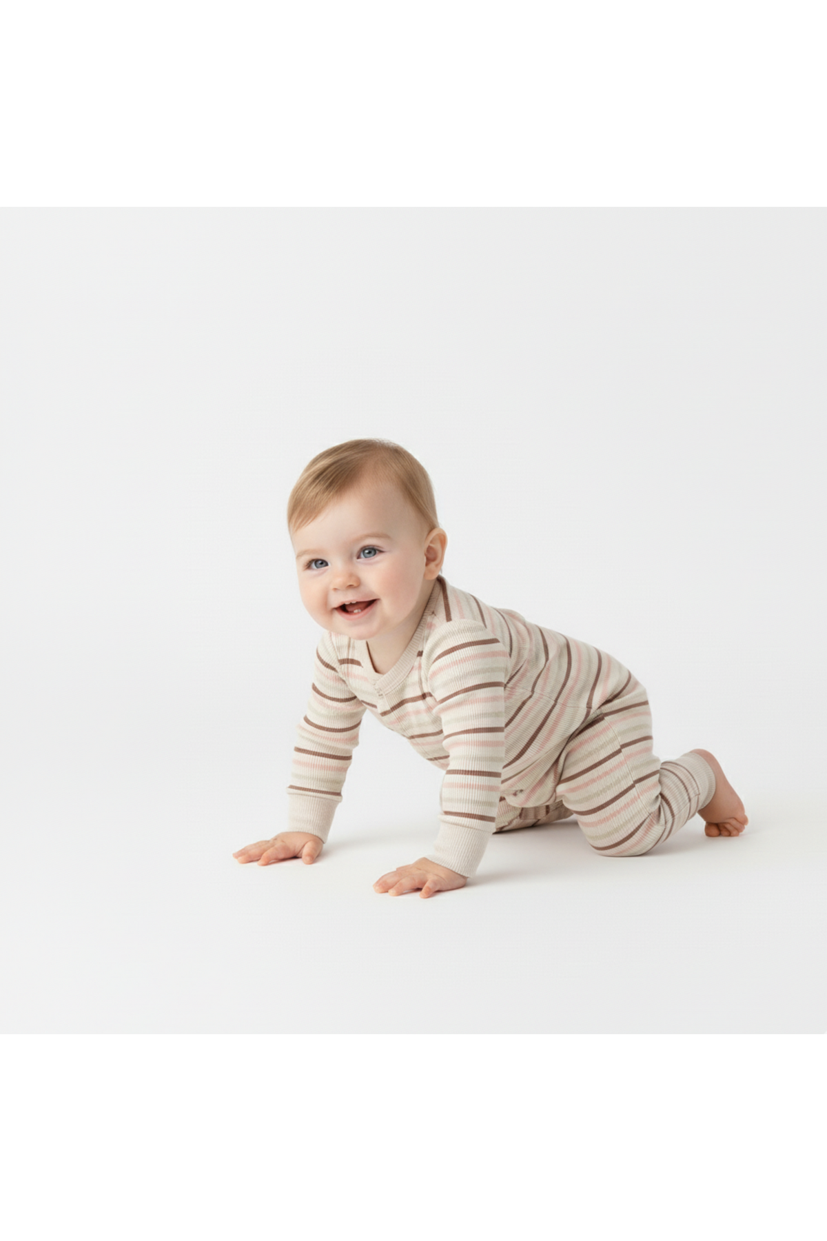 A smiling baby crawls on a light background, wearing a soft, organic cotton romper with Terra Stripes. The outfit features a cozy design, perfect for comfort and easy changing.