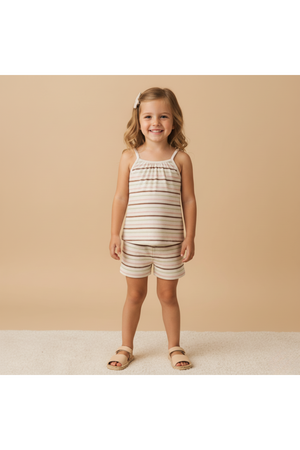 A young girl smiles while wearing an organic cotton tank top and shorts set featuring soft, striped patterns in earthy tones.