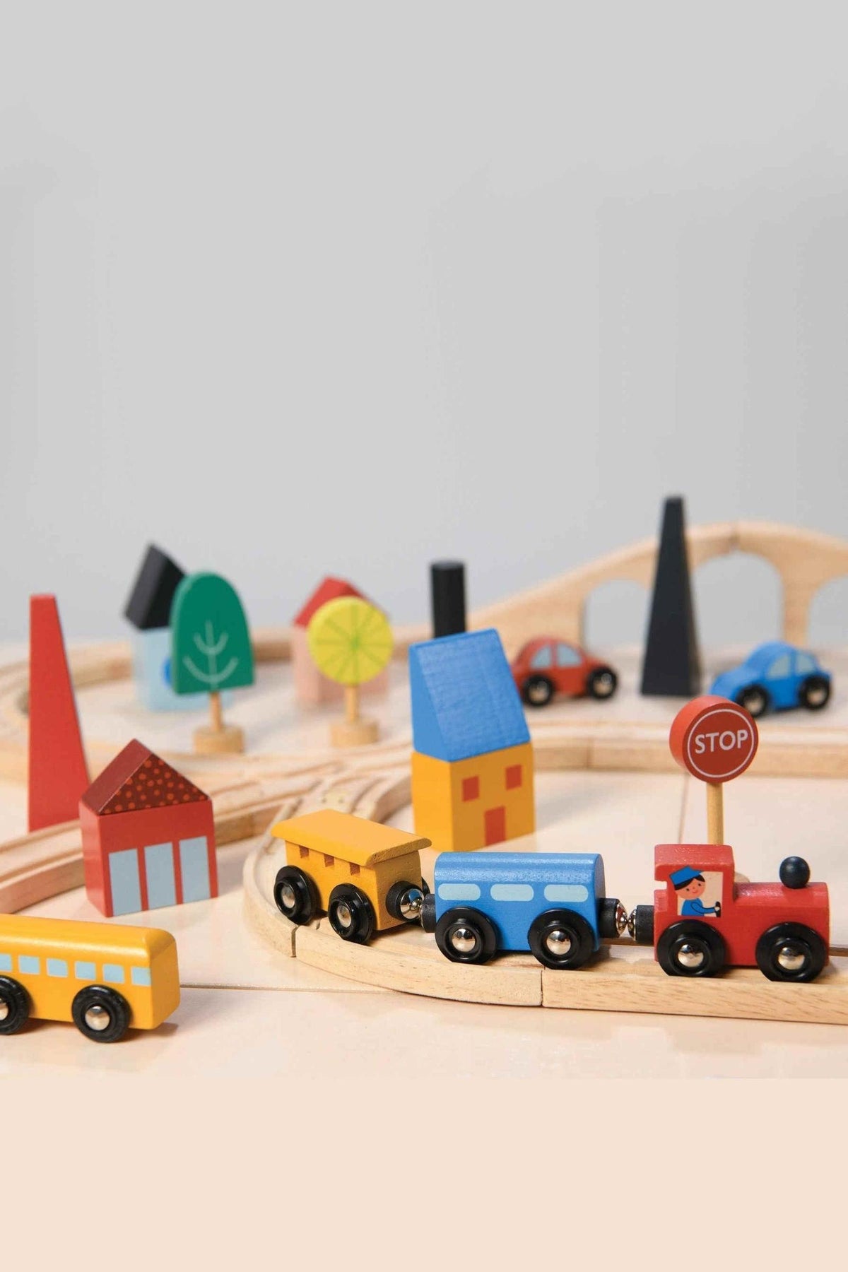 Colorful wooden train set with tracks, houses, trees, and cars, featuring sustainable materials in a playful town scene.