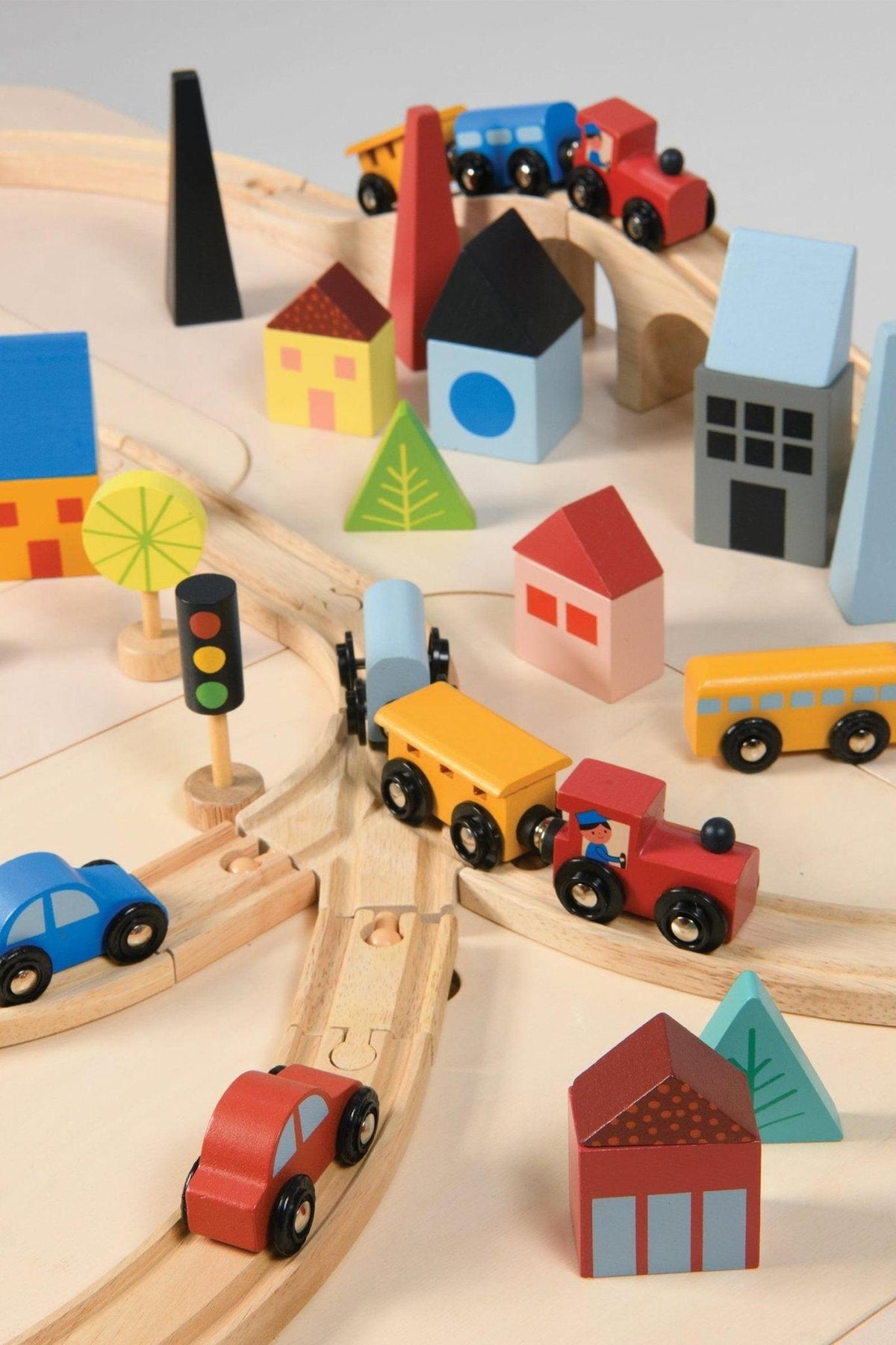 Colorful wooden train set with cars, buildings, trees, and traffic light on a wooden track. Eco-friendly play scene.
