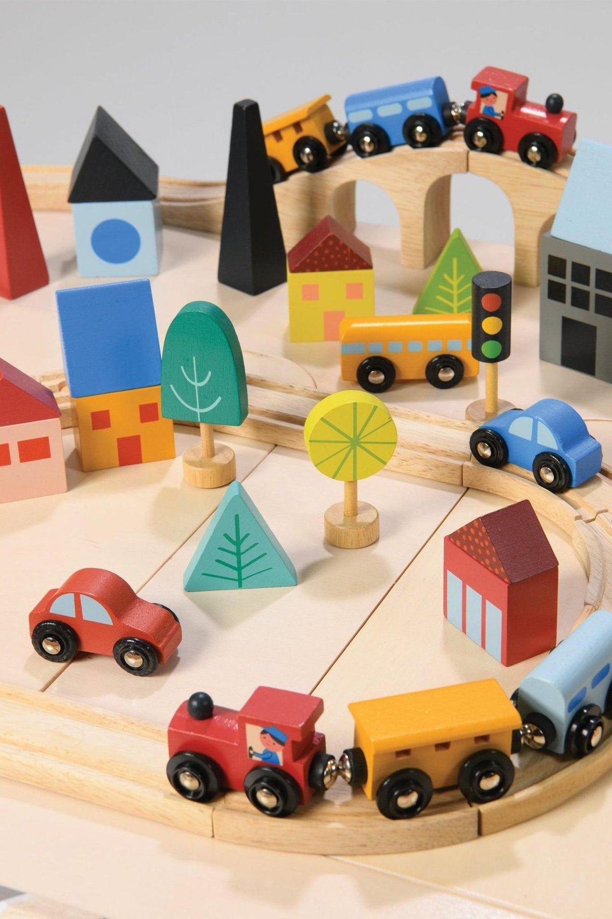 Colorful wooden train set with cars, buildings, and trees on a track, featuring sustainable materials and playful design.
