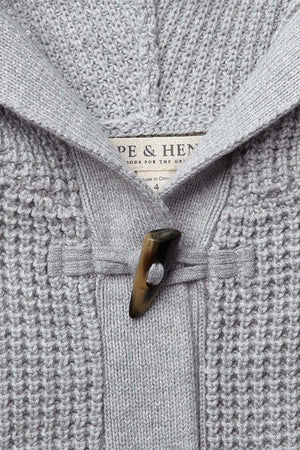 Close-up of a gray hooded sweater with a waffle stitch texture, featuring a faux horn toggle and visible brand label.