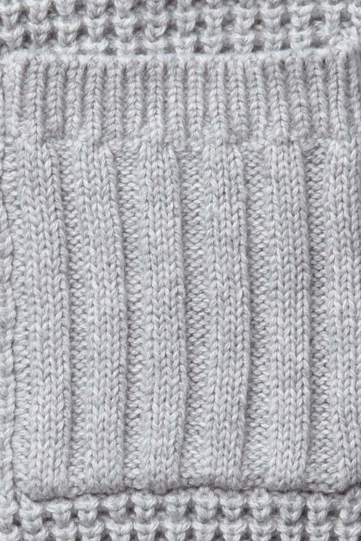 Close-up of a textured gray knit fabric featuring ribbed and waffle stitch patterns, showcasing its soft organic cotton composition.