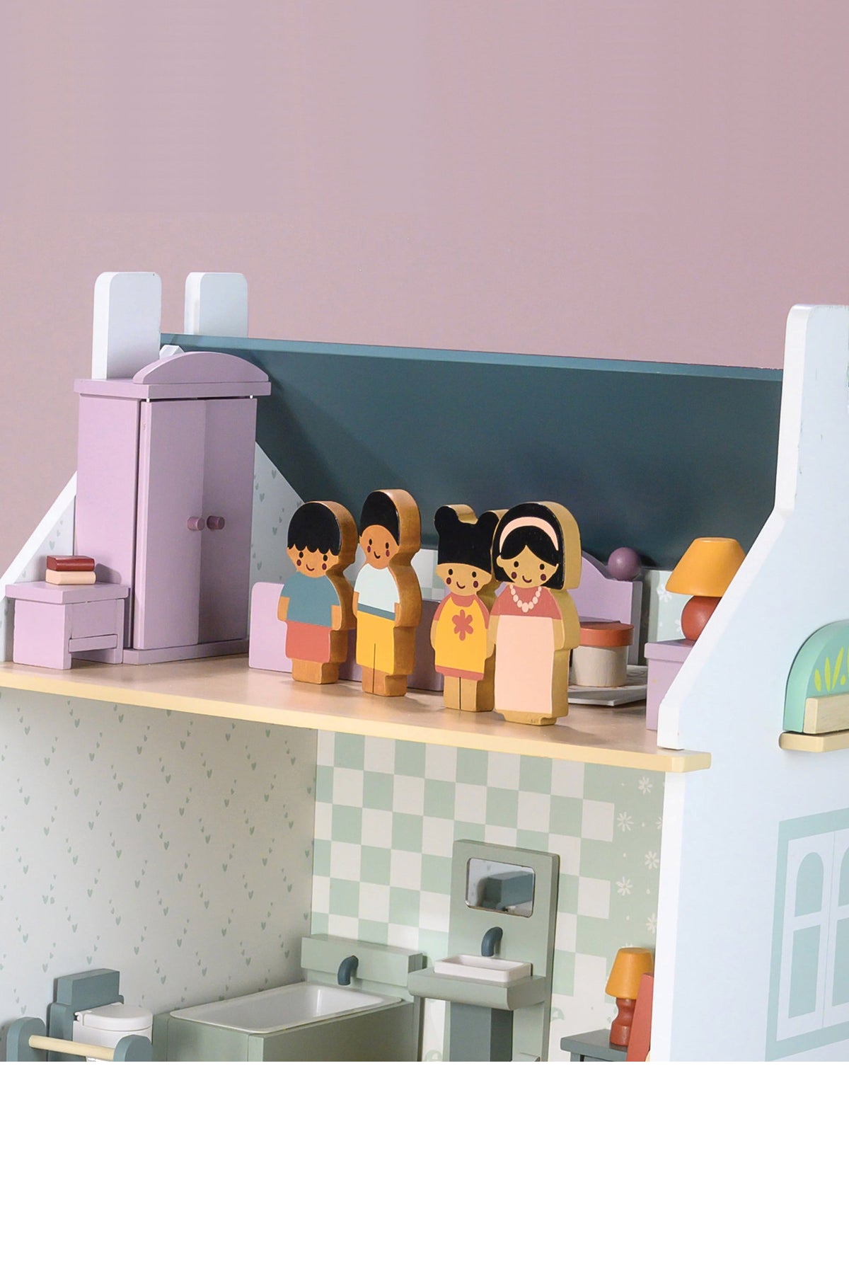 Children's toy dollhouse with dolls and furniture on a pink background