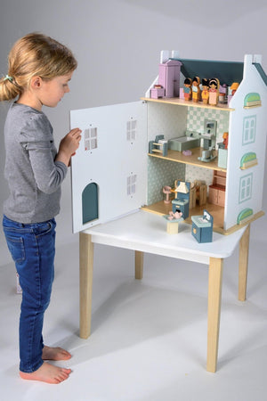 A child interacts with a colorful wooden dollhouse featuring multiple rooms and detailed accessories. The dollhouse is designed for imaginative play, highlighting its sustainable and eco-friendly materials.